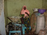 Woman standing beside groundnut milling machine